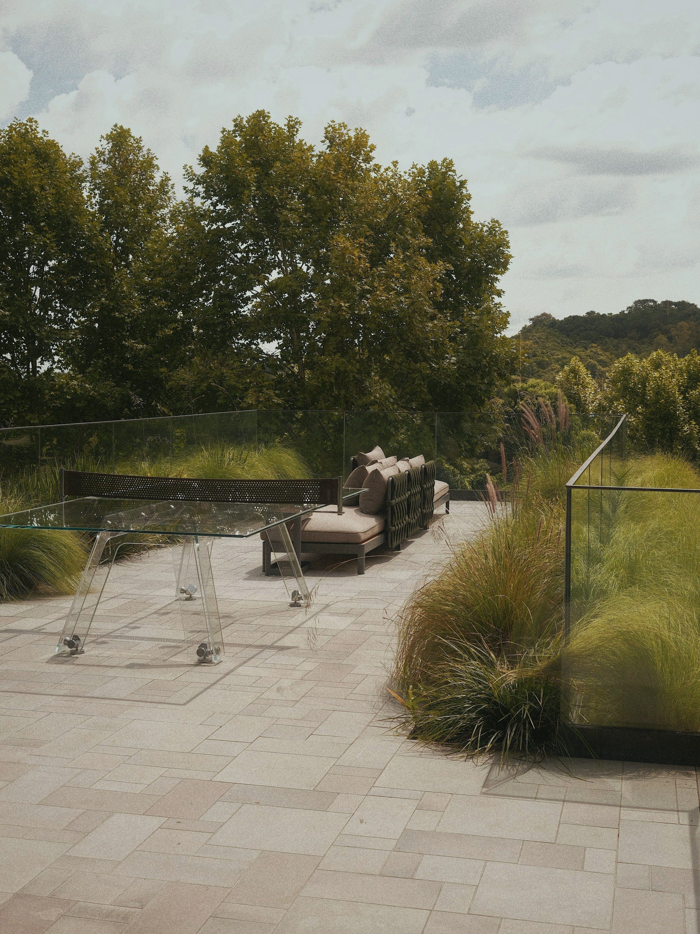 Drifts of grasses spilling over the paving along the glazed edge of the terrace.