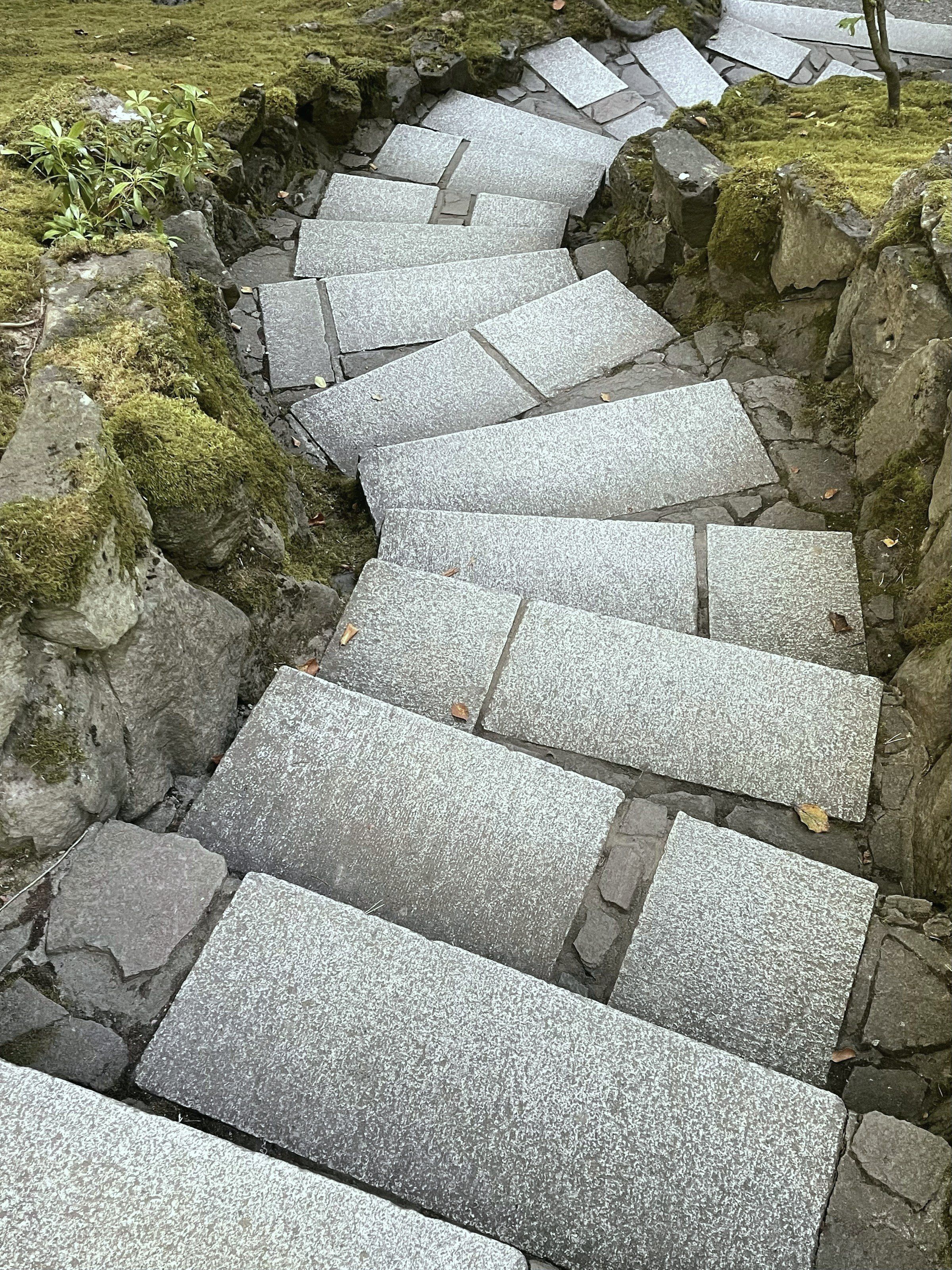 Granite slabs laid as steps down a slope, moss growing tight to the edge of every tread.