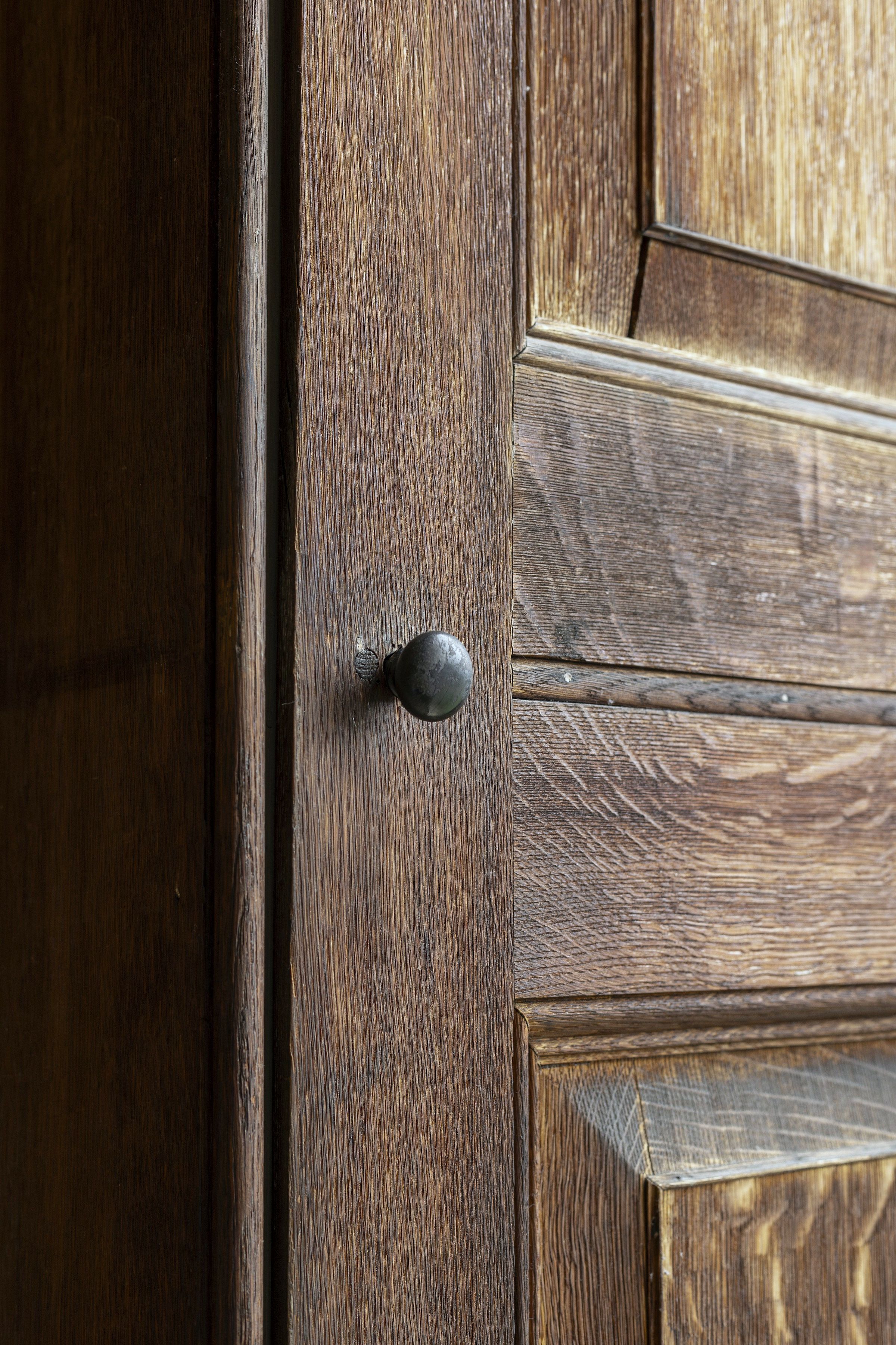 Joinery close-up: the cross-grain junction of stile and rail on an oak panelled door, with an aged knob.