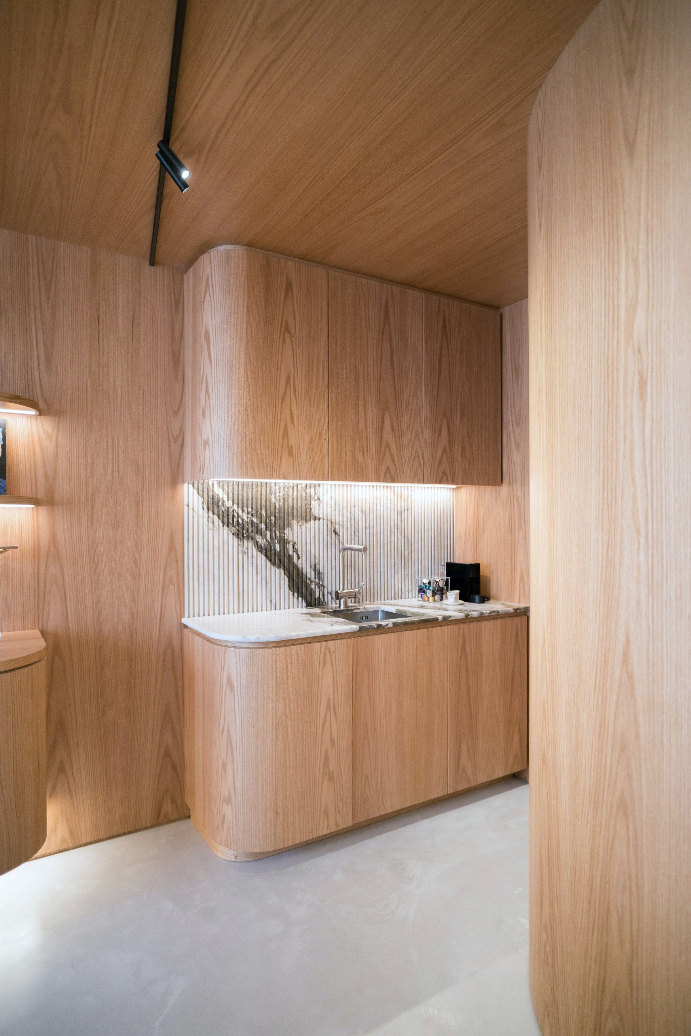 The kitchen: oak-lined joinery with a curved end return, under a veined stone worktop and matching backsplash.