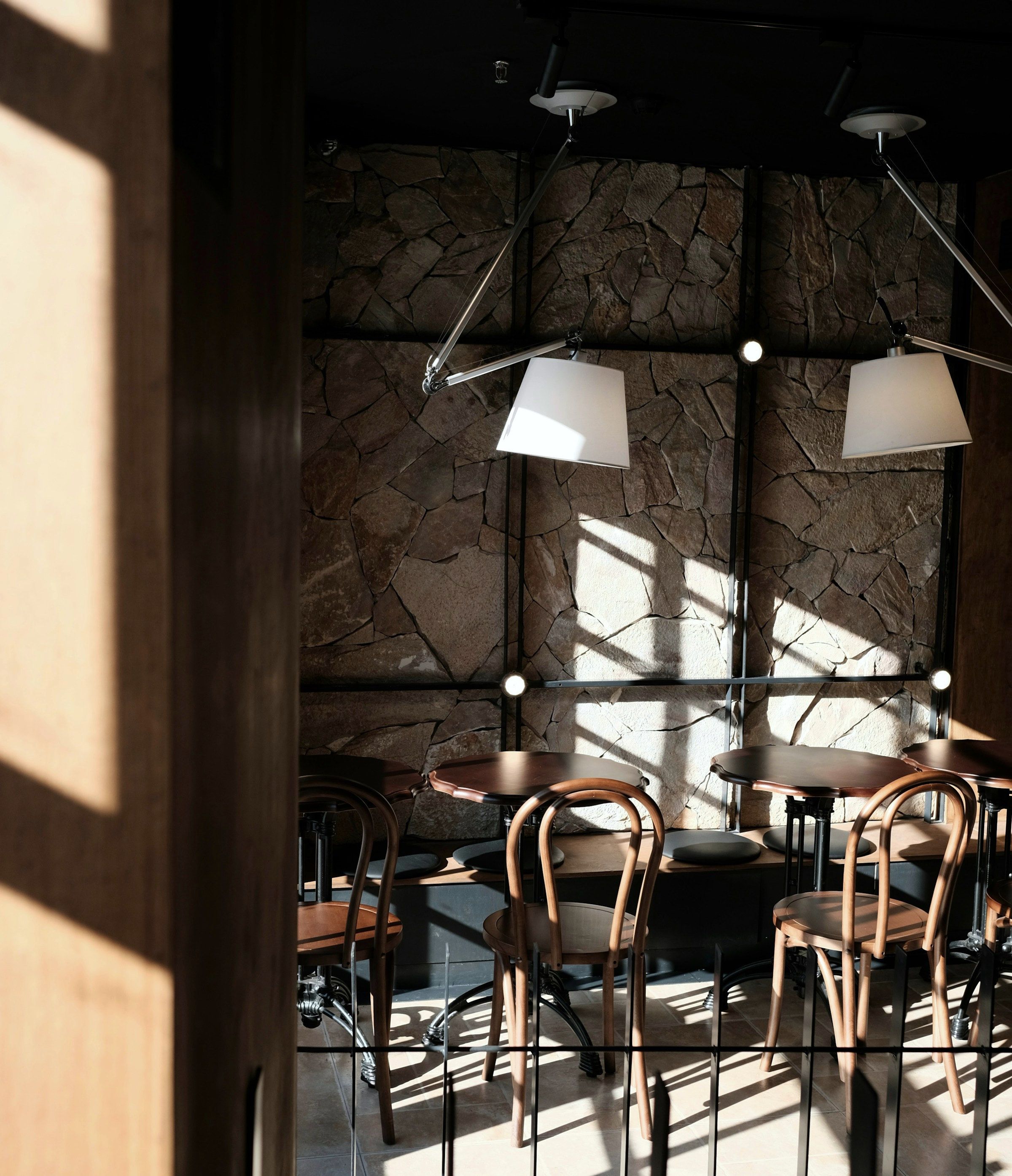 The dining room at Restaurant Kalk: split-face stone walls and bentwood chairs, with hard bars of afternoon sun laid across the floor.