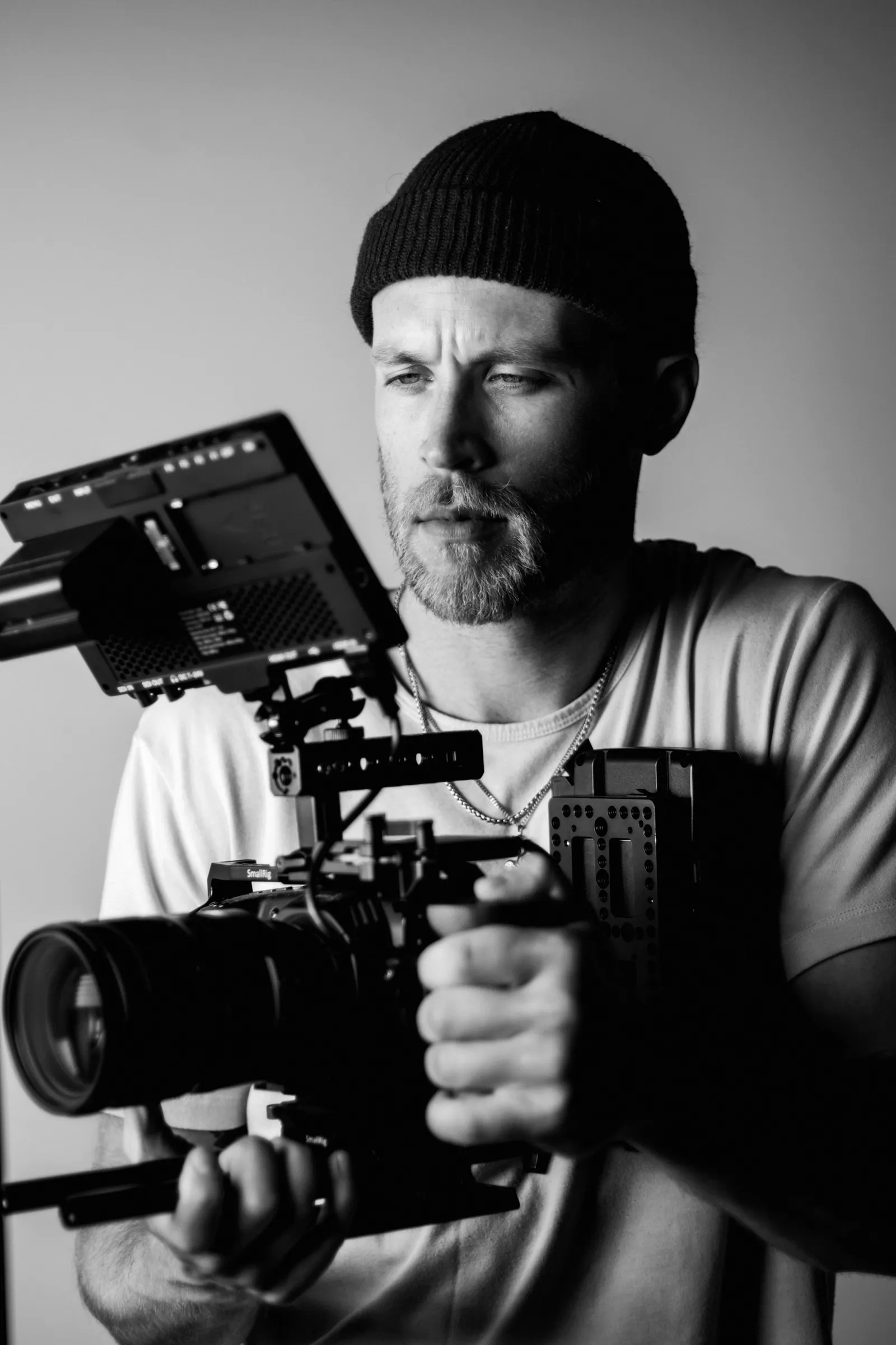 A photographer in a beanie holding a cinema camera rig