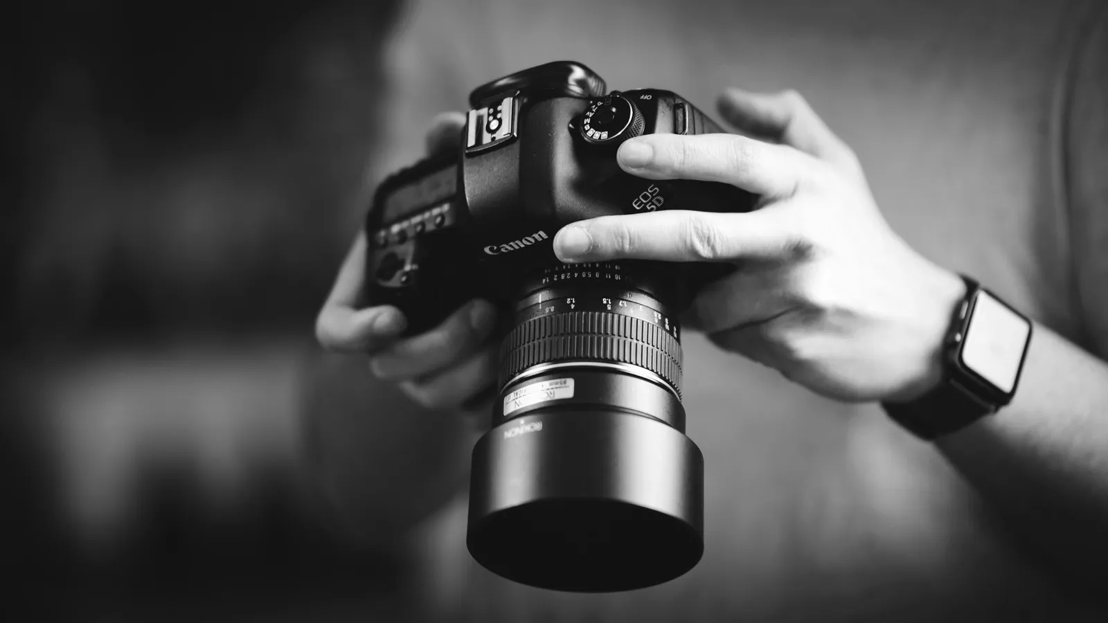 Two hands holding a camera with a long lens