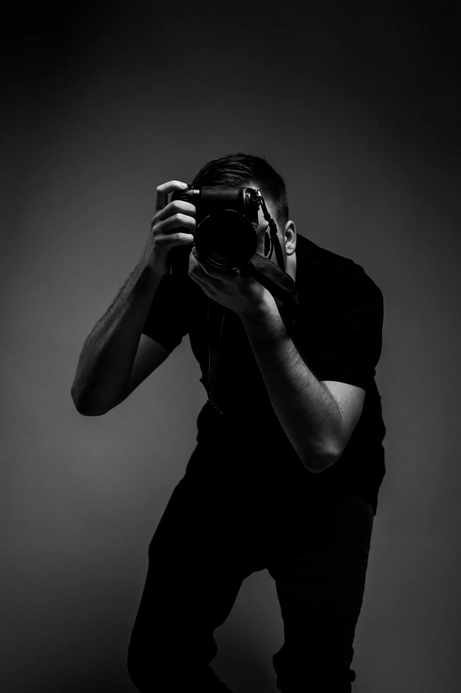 A photographer in a dark room raising a camera to his eye