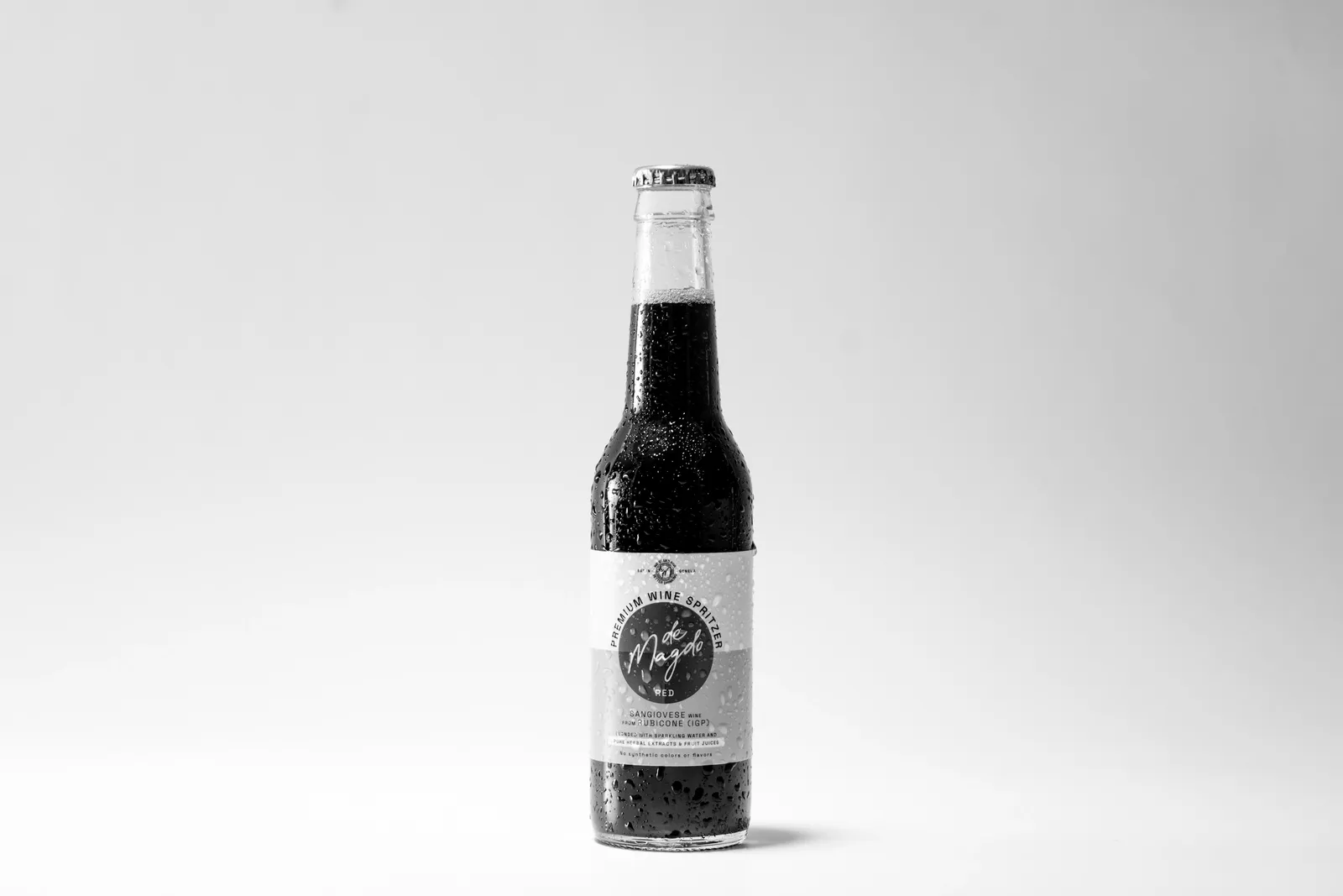 A single bottle of dark soda standing on white
