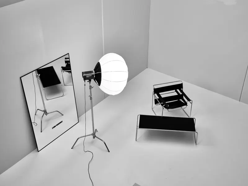 A small white studio with a lantern light, a mirror and a stool