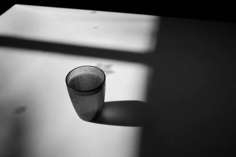 A glass tumbler casting a long shadow on a table