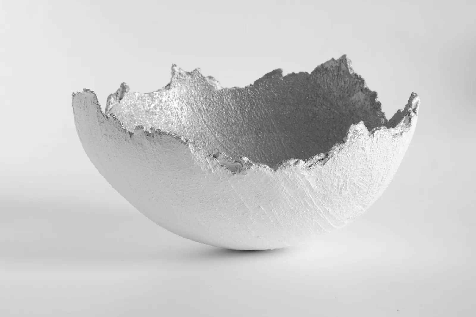 A white bowl with a rough broken rim on a pale background
