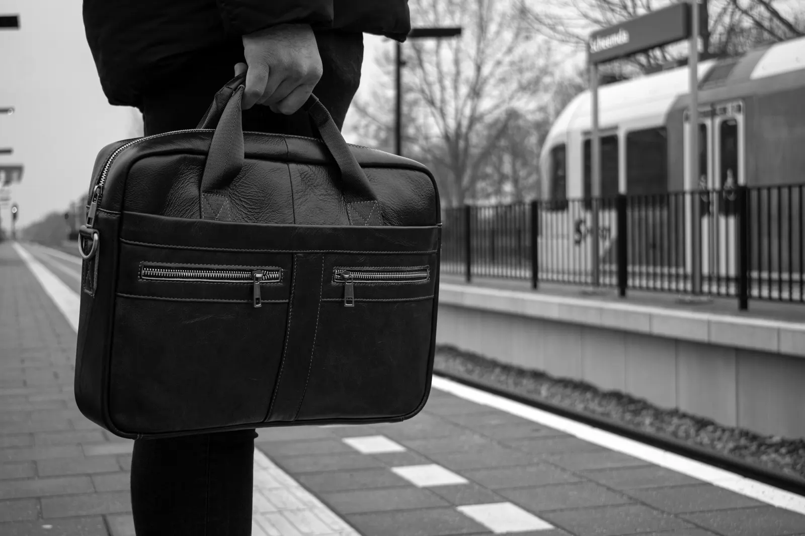 A commuter holding a leather briefcase on a train platform