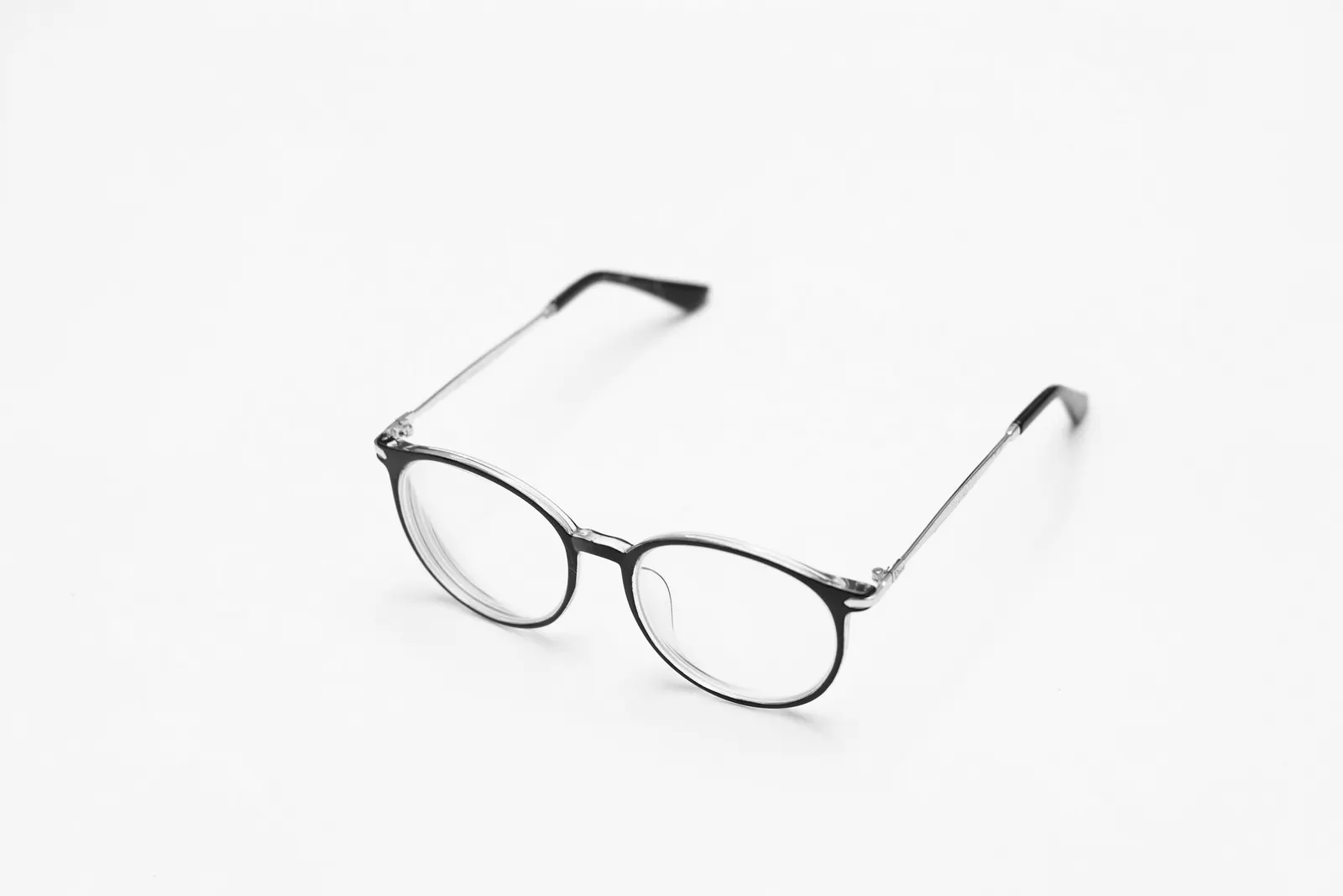 A pair of thin round glasses on a white surface