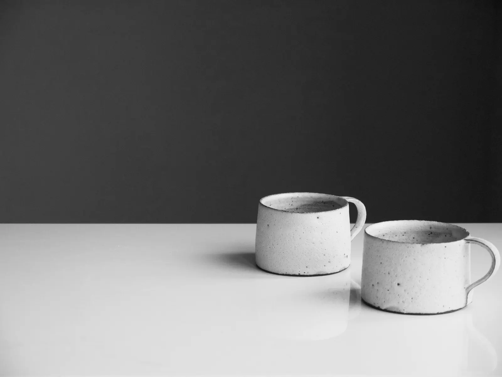 Two small stoneware mugs on a white table