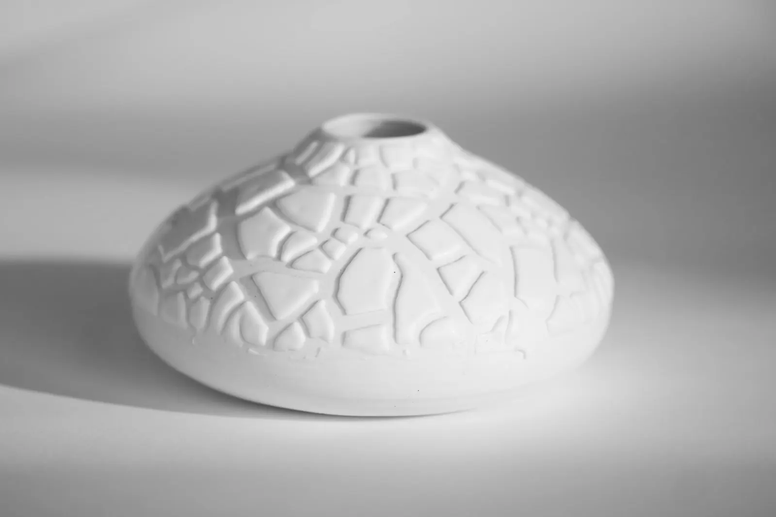 A low white porcelain vessel with a crackled texture