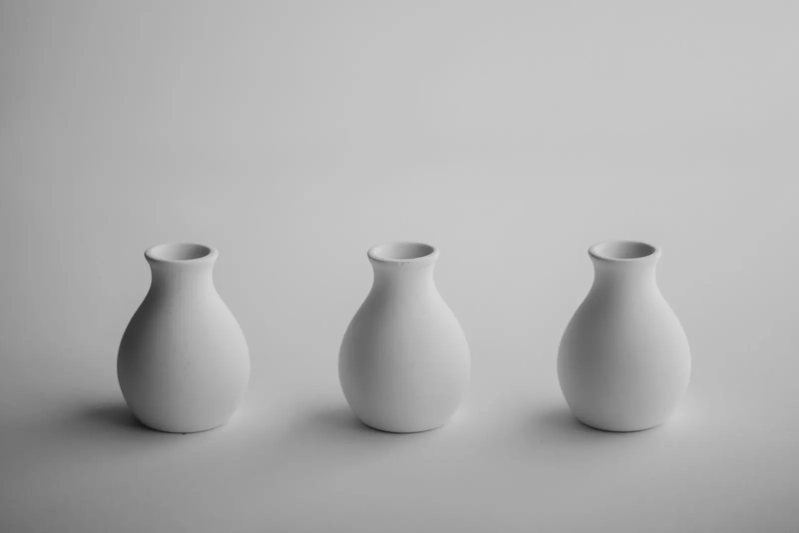 Three white bud vases in a row