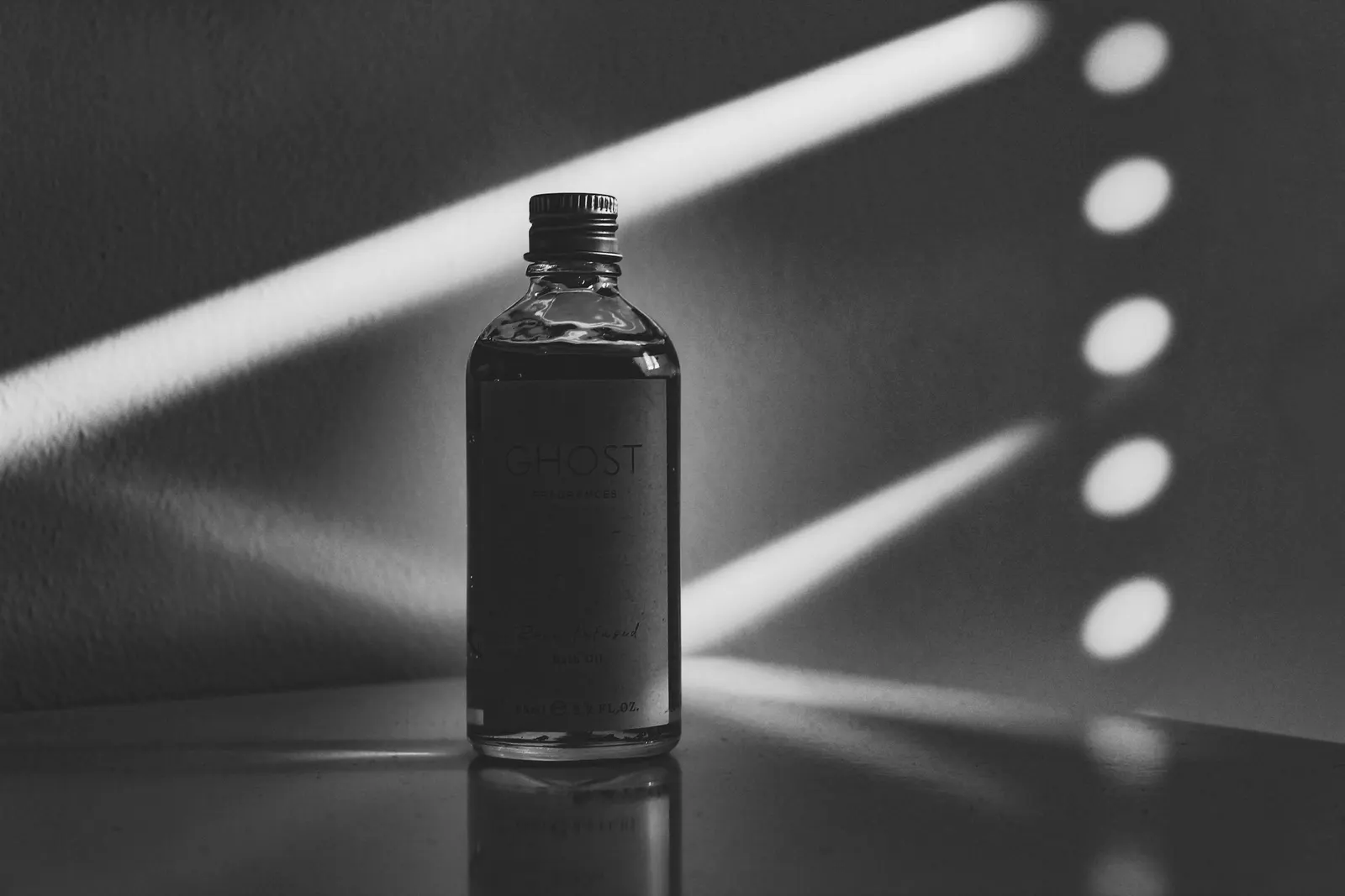 A small glass bottle lit by stripes of window light