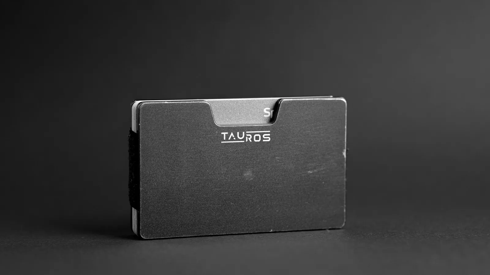 A slim metal card wallet standing on a dark surface
