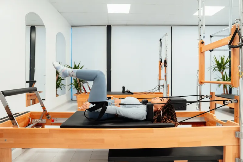 A pilates reformer class in a white studio