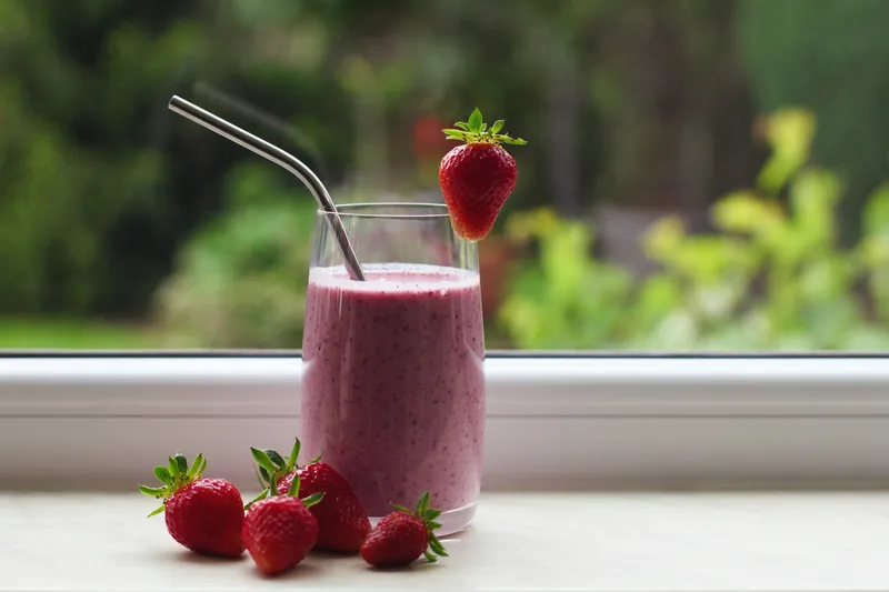 A pink berry smoothie by a sunny window